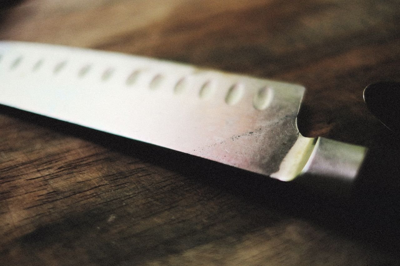 Detalle de la hoja de un cuchillo de sierra profesional sobre una tabla de madera